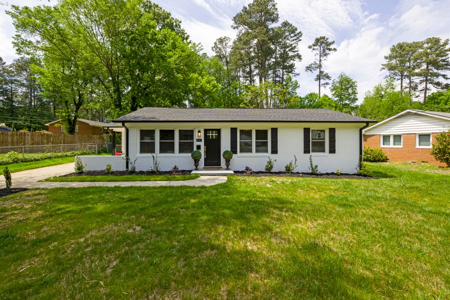 White single-story ranch house with a front lawn and mature trees